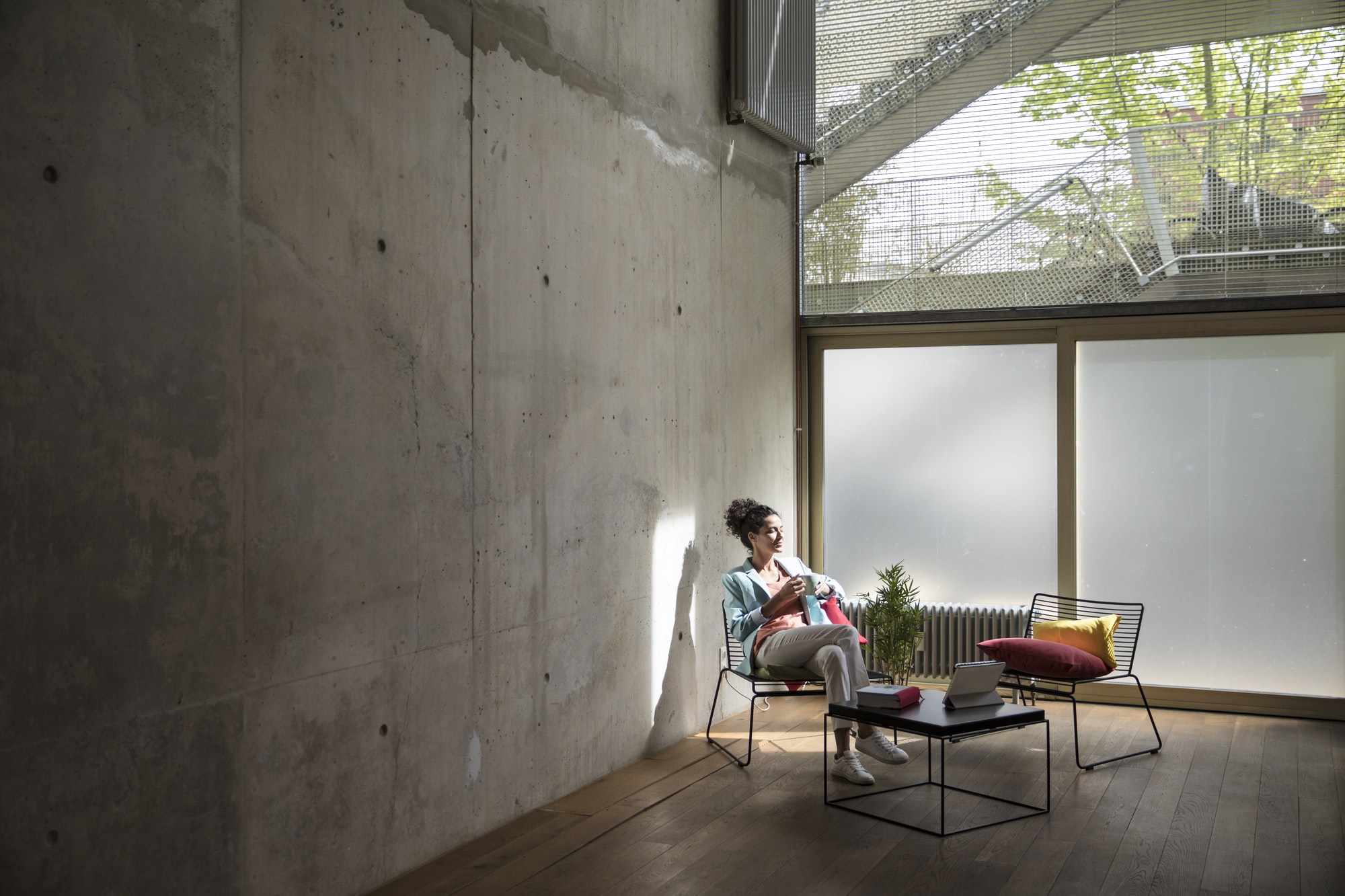 Businesswoman sitting in a loft at concrete wall having a break